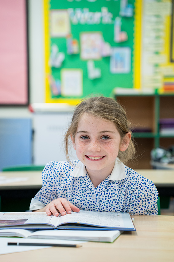 girl pupil sitting at the desk in the classroom