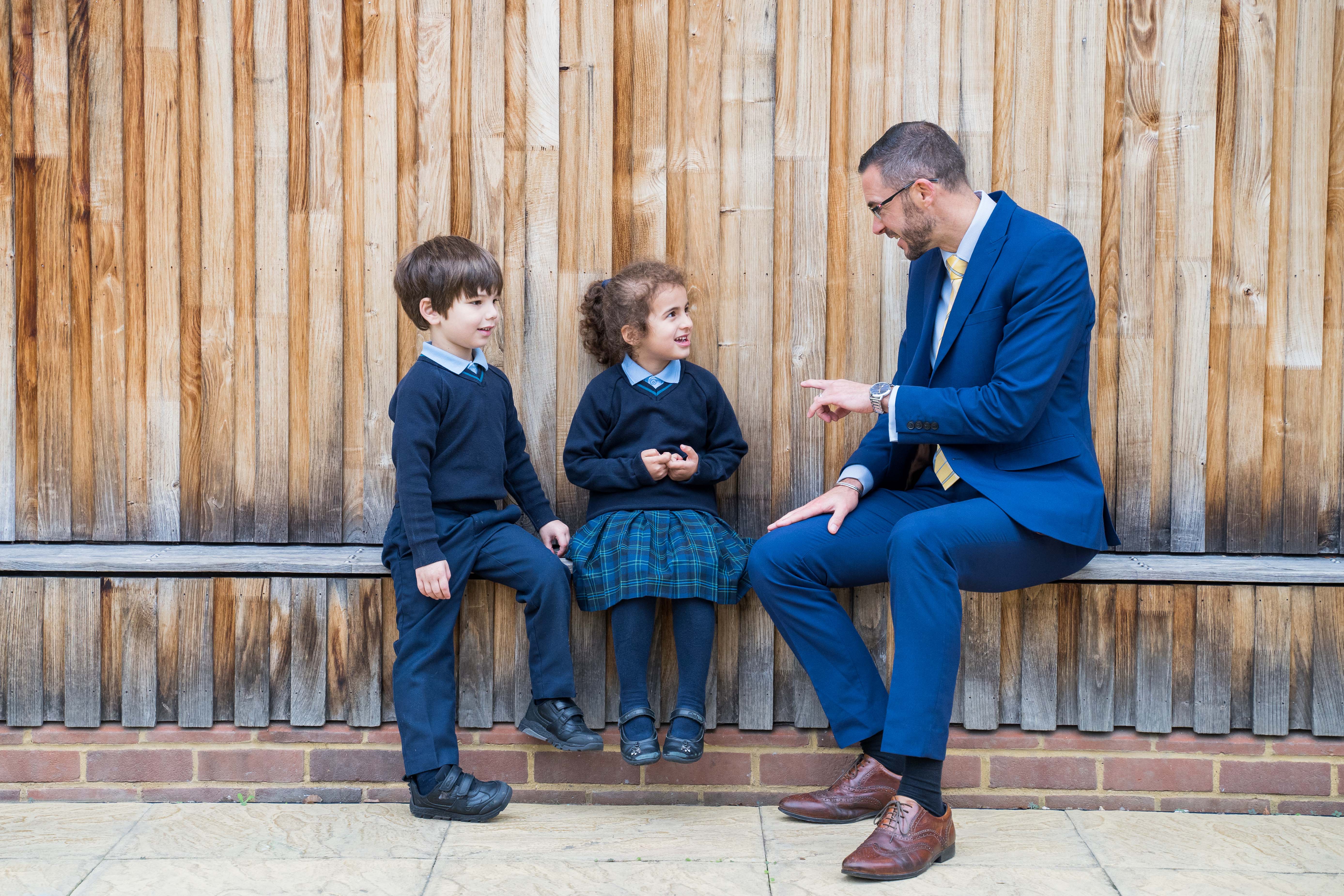 Pre-Prep boy and girl talking to teacher in the outdoor space at Halstead St Andrew's