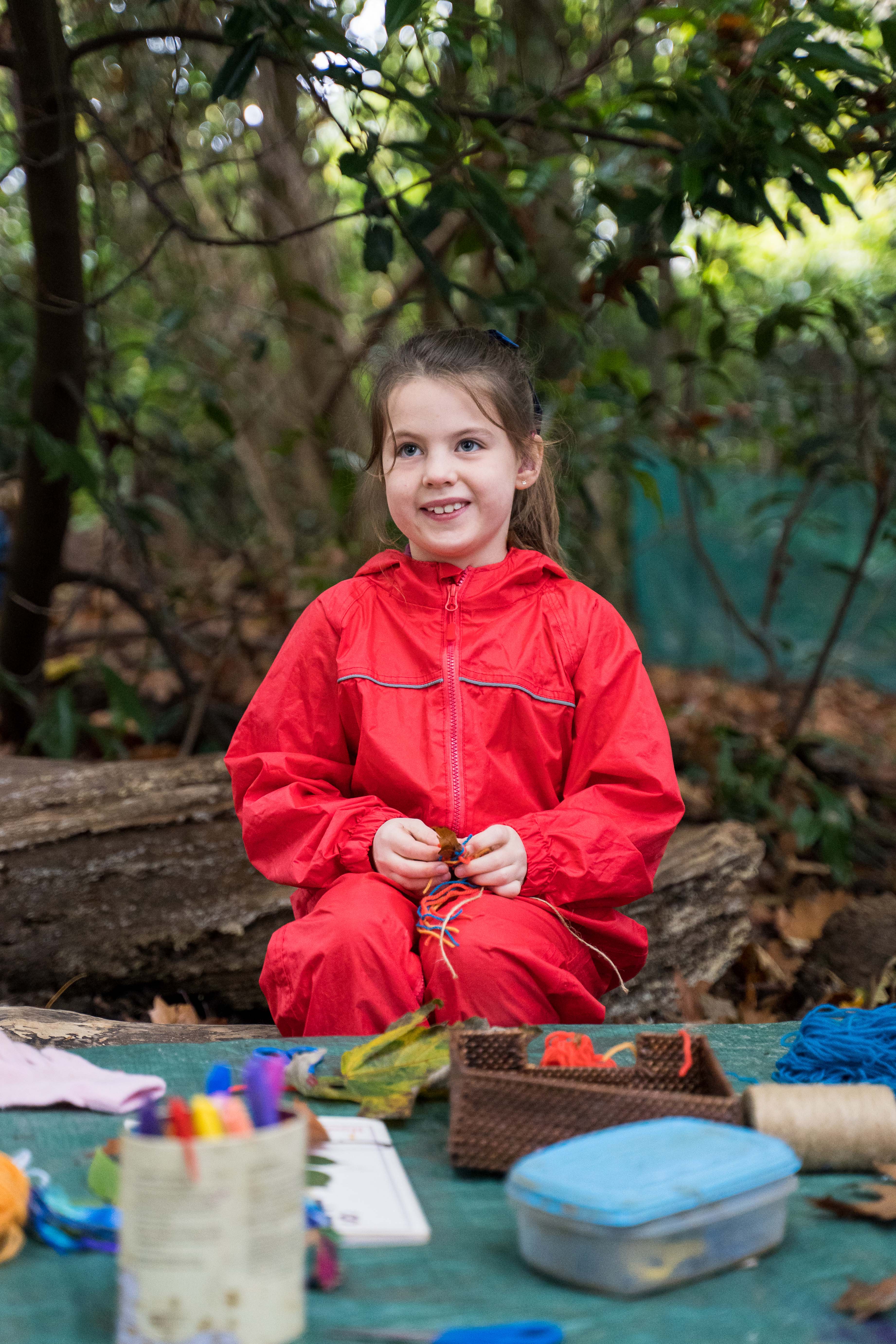 Pupil in red waterproofs in Forest School