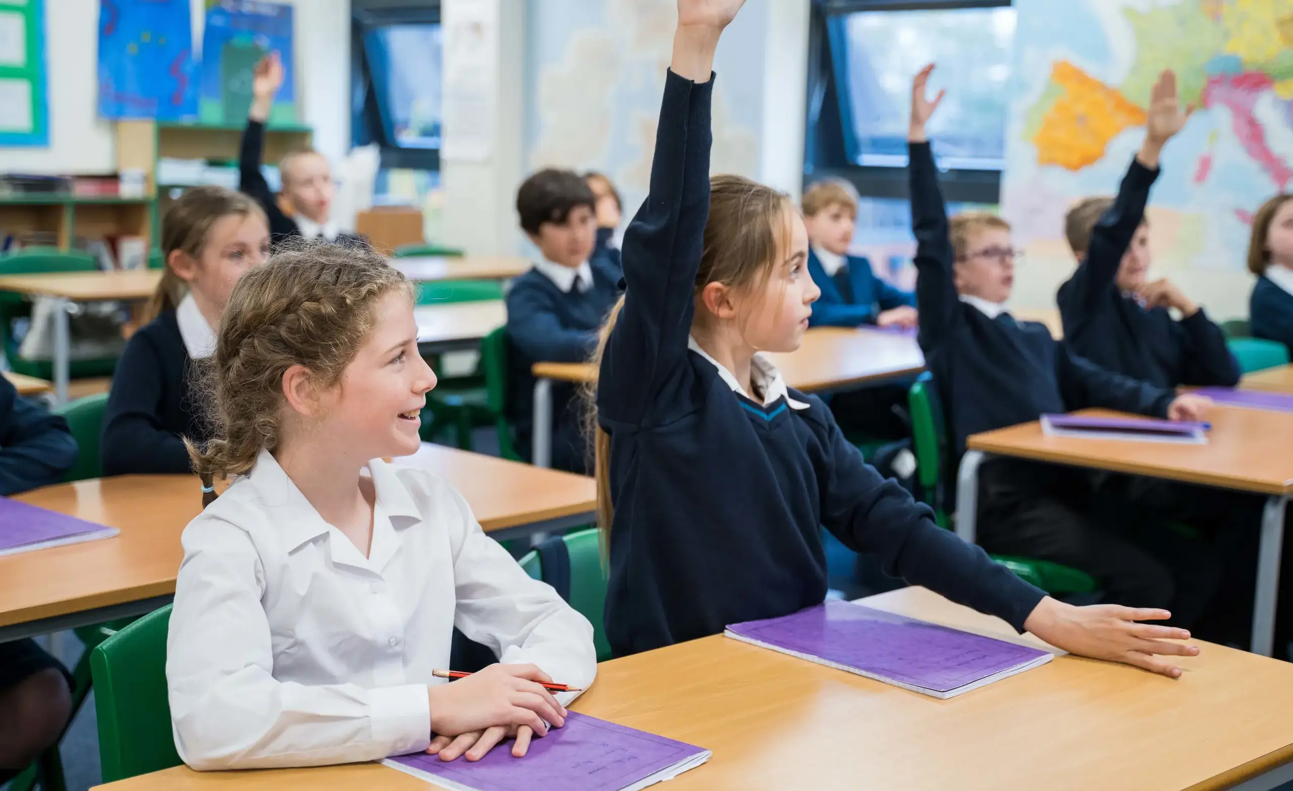 Classroom with pupils with hands up answering a question