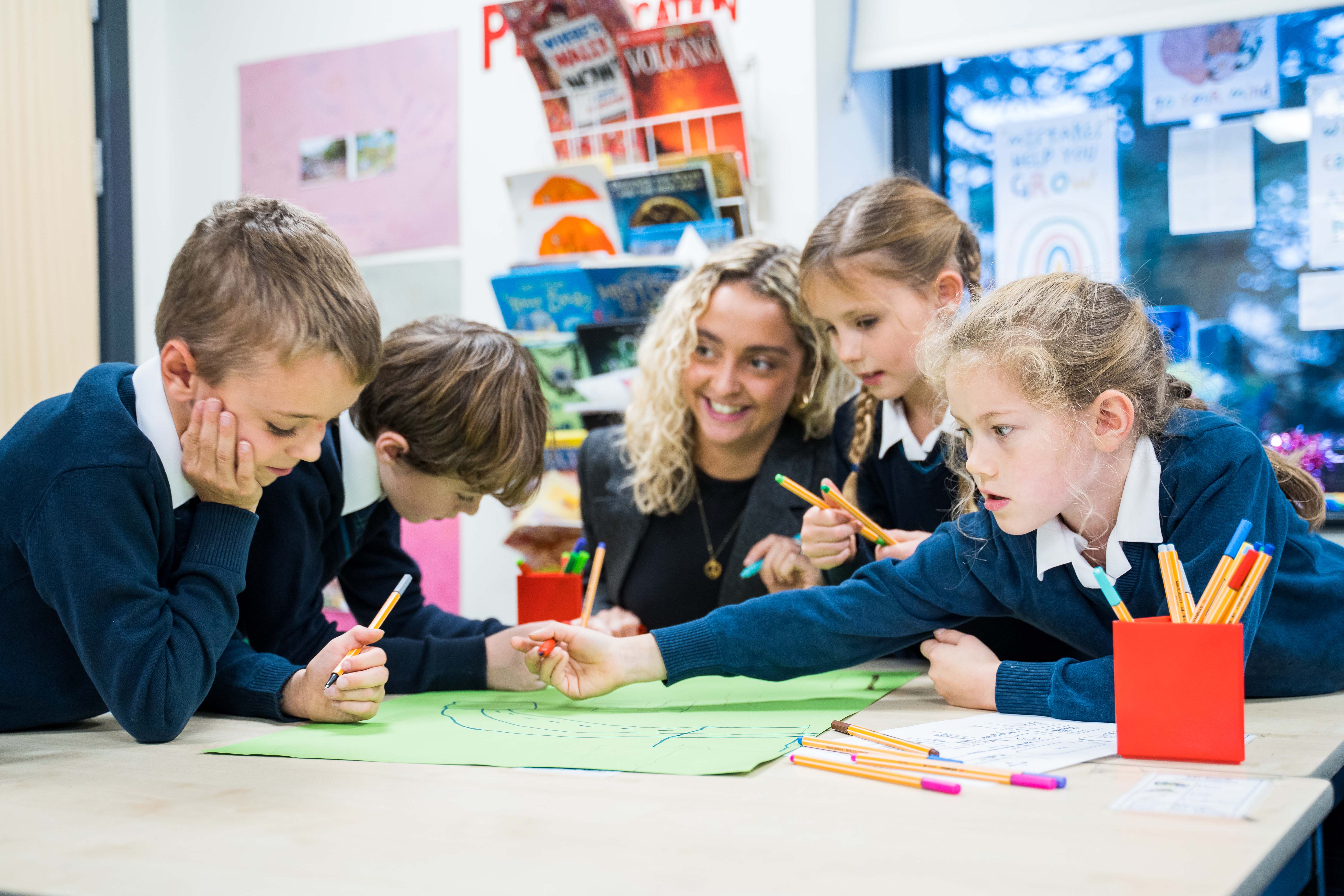 Children with teacher around a desk in the classroom
