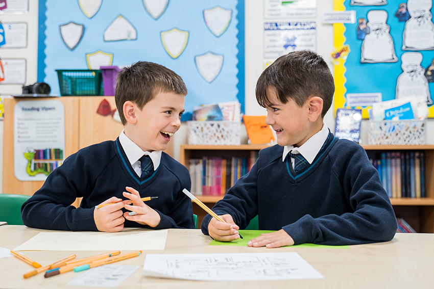Two boys in a classroom sharing a joke