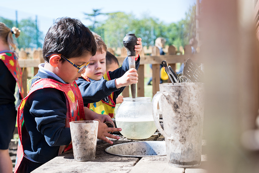 Nursery children at Halstead St Andrew's playing in the mud kitchen outside