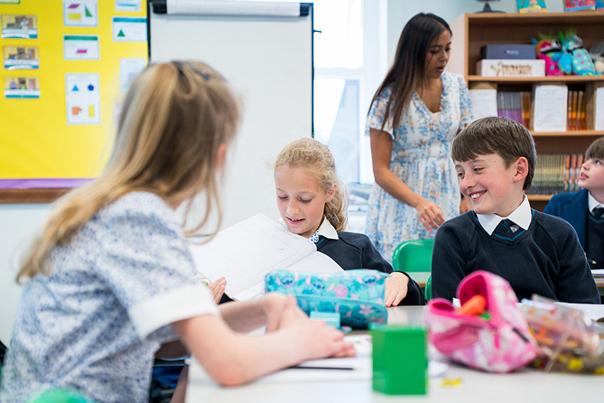 Pupils in a classroom with teacher in the background